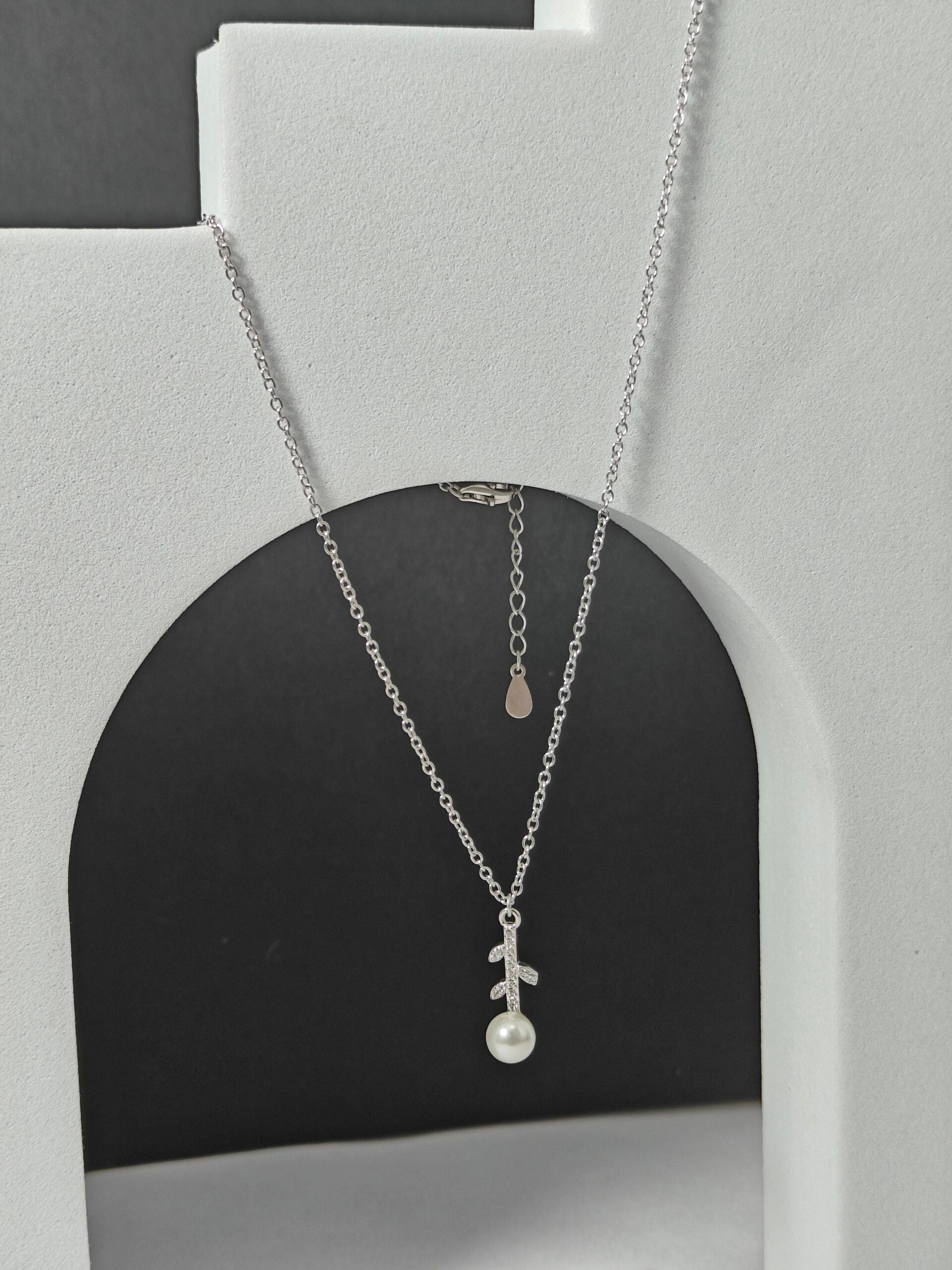 Silver necklace with a pendant on a gray stand